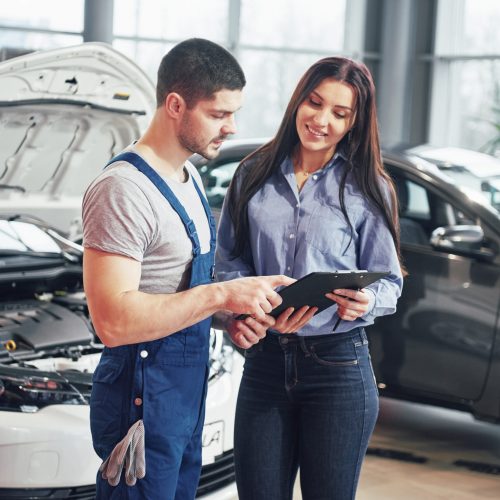 A man mechanic and woman customer discussing repairs done to her vehicle.